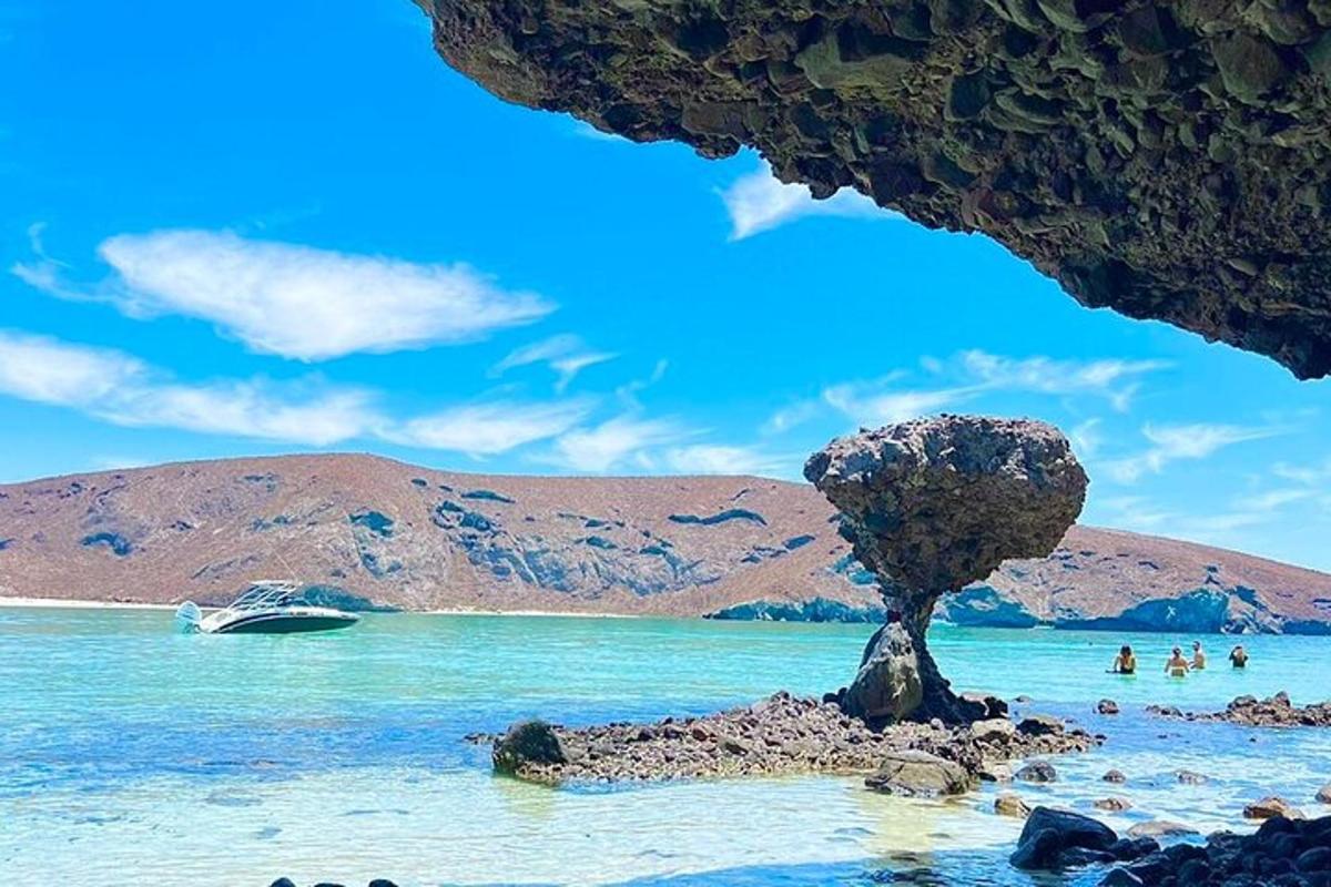 una roca a la platja amb un vaixell a l'aigua
