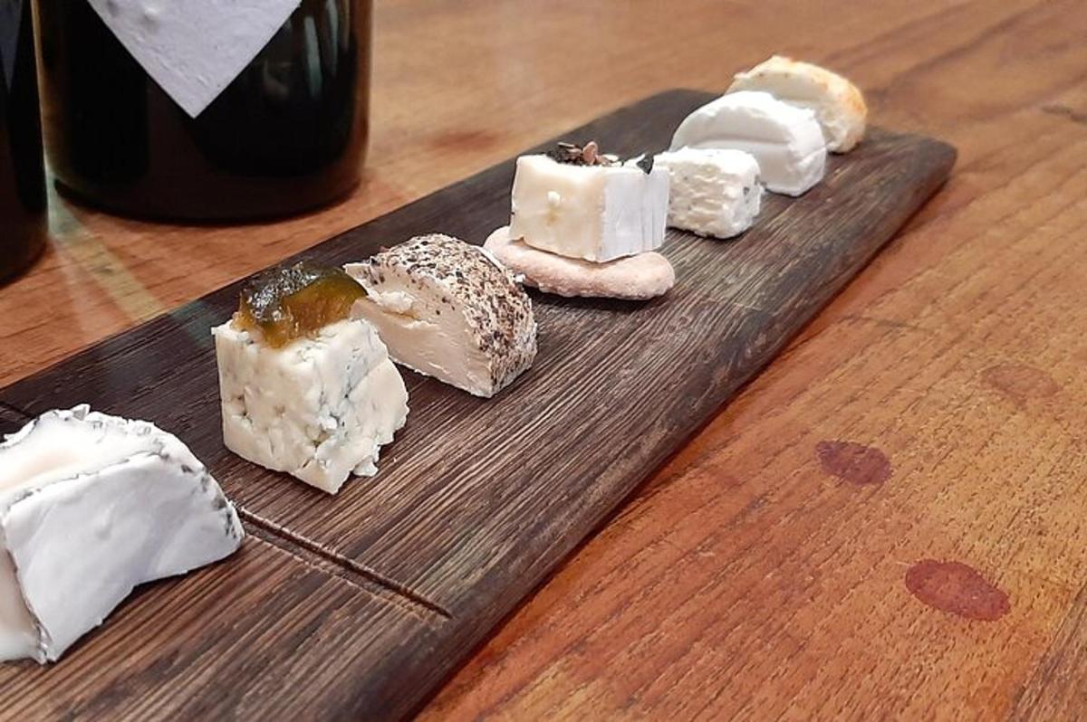 eine Gruppe von Käse auf einem Schneidebrett mit einer Flasche Wein