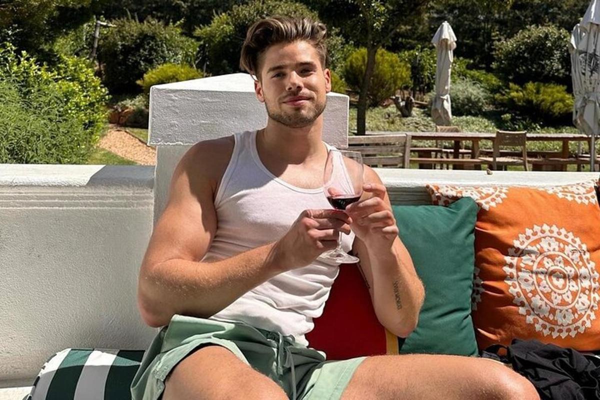 un uomo seduto su una panchina con in mano un bicchiere di vino