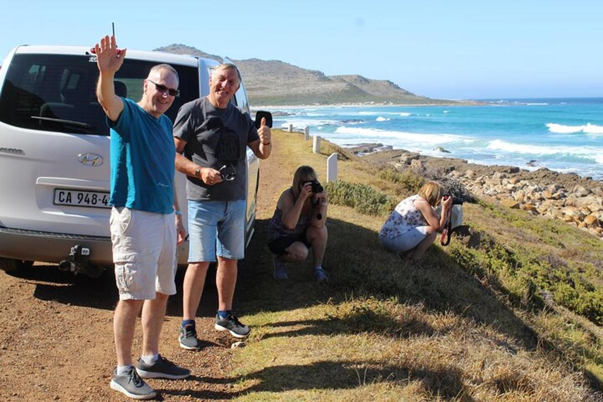 a group of people standing next to a car on a beach