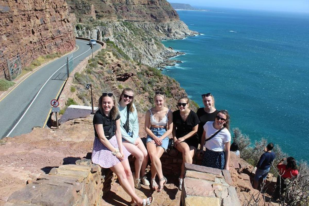a group of people sitting on a cliff next to the ocean