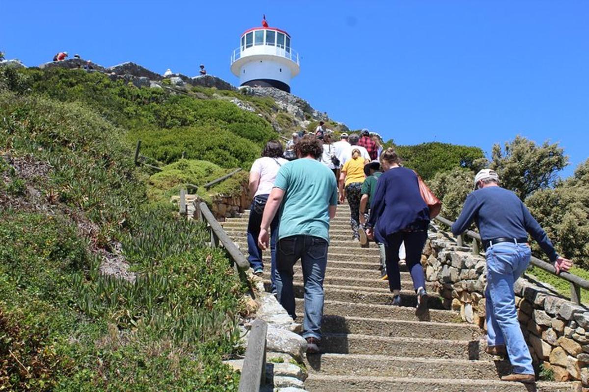 a group of people walking up the stairs to a lighthouse