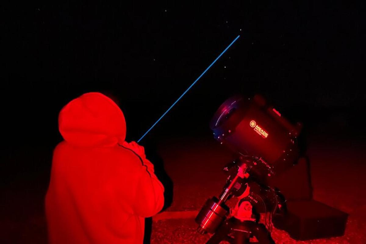 osoba v červené mikině s kapucí stojící vedle motorky
