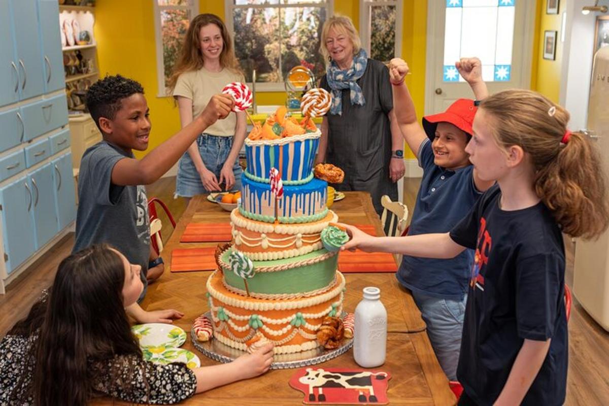 a group of people standing around a table with a birthday cake