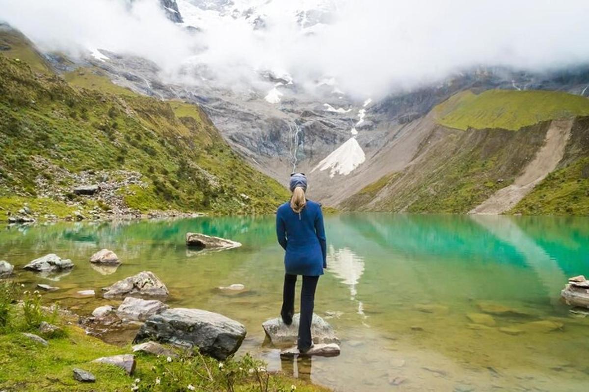 seorang wanita berdiri di atas batu di tasik gunung