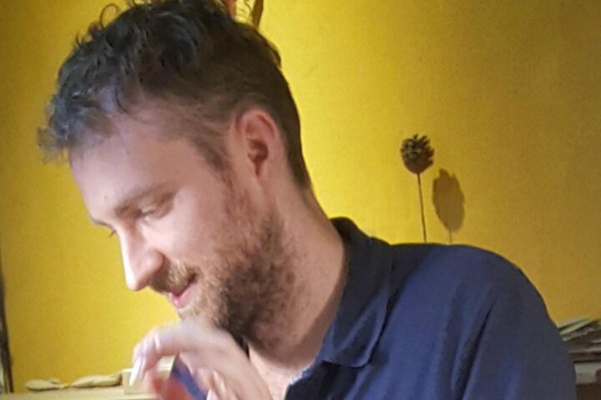 maður með skegg sem heldur tannbursta í munninum
