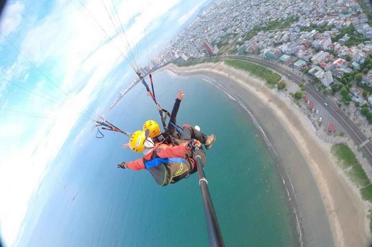 Un hombre volando por el aire mientras monta un paracaídas sobre el agua.