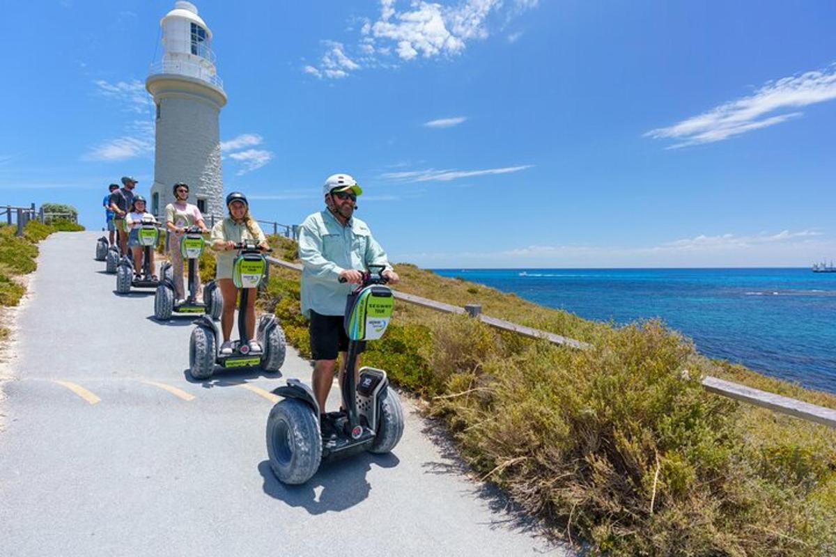 Skupina lidí jezdících na segwayích poblíž majáku