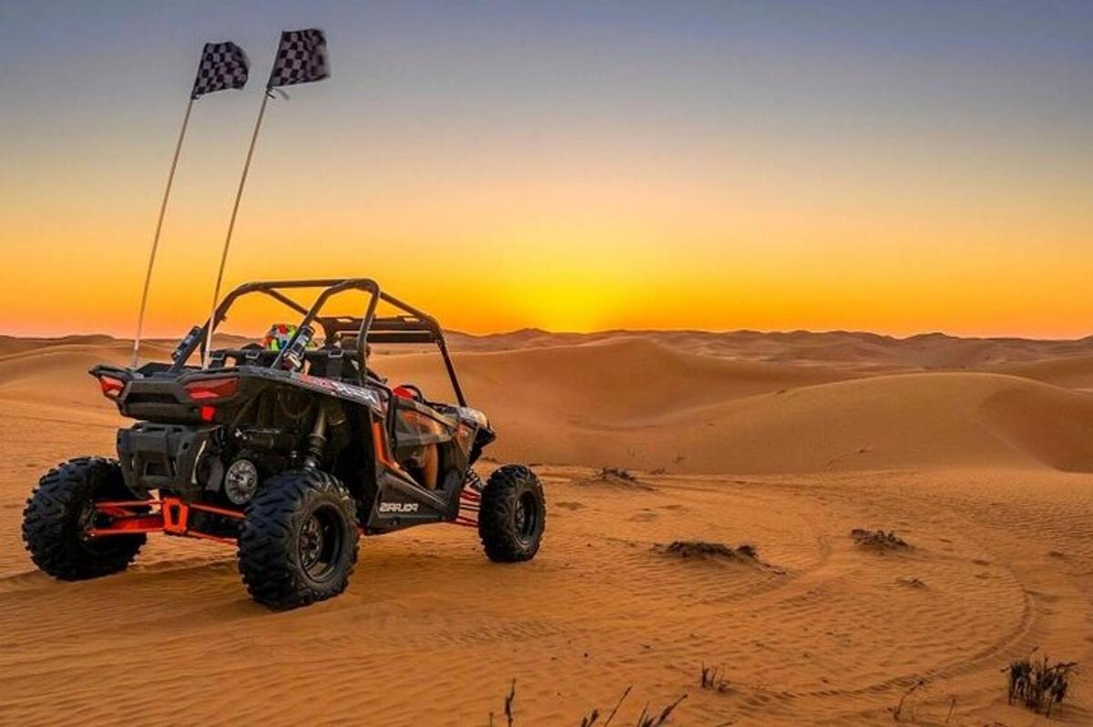 um quadriciclo no deserto com o pôr do sol ao fundo