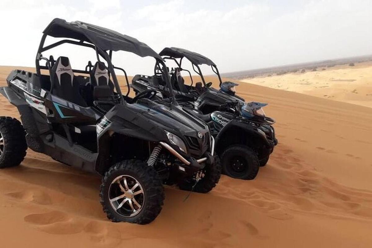 dois quadriciclos estacionados na areia do deserto