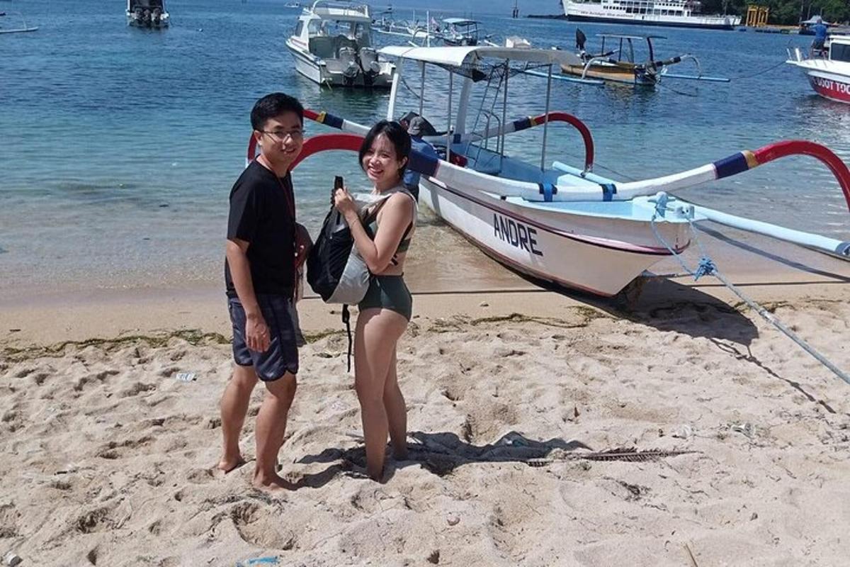 moški in ženska stojita na plaži poleg čolna