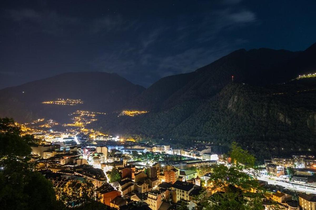 una vista d'una ciutat de nit amb muntanyes
