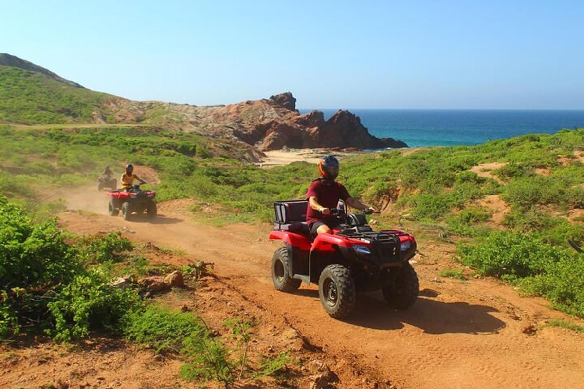 due persone in quad su una strada sterrata vicino all'oceano