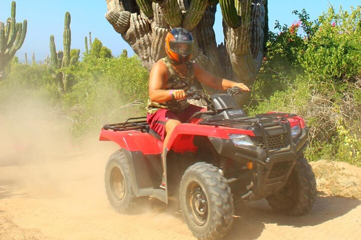 una persona che guida un quad rosso su una strada sterrata