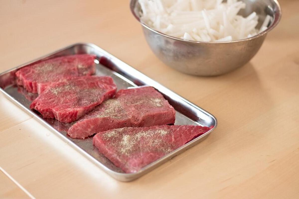 kuali daging di atas kaunter dengan semangkuk bawang