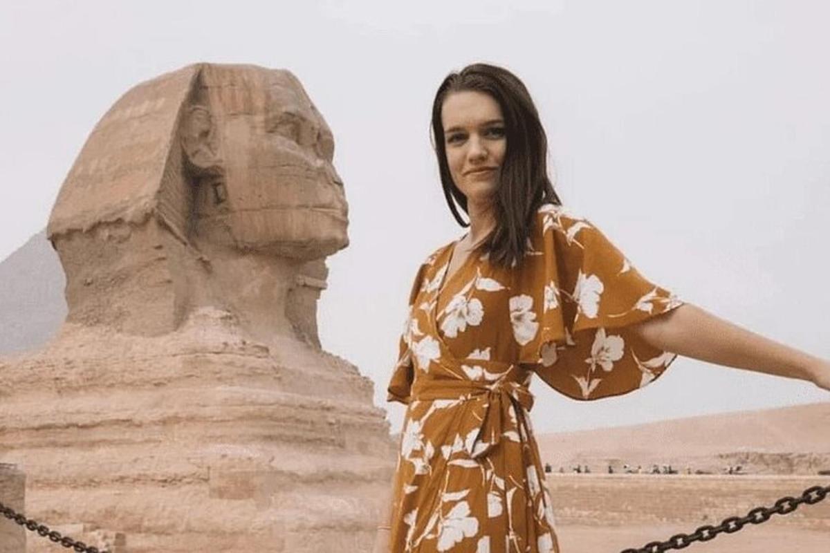 seorang wanita berpakaian berdiri di sebelah patung