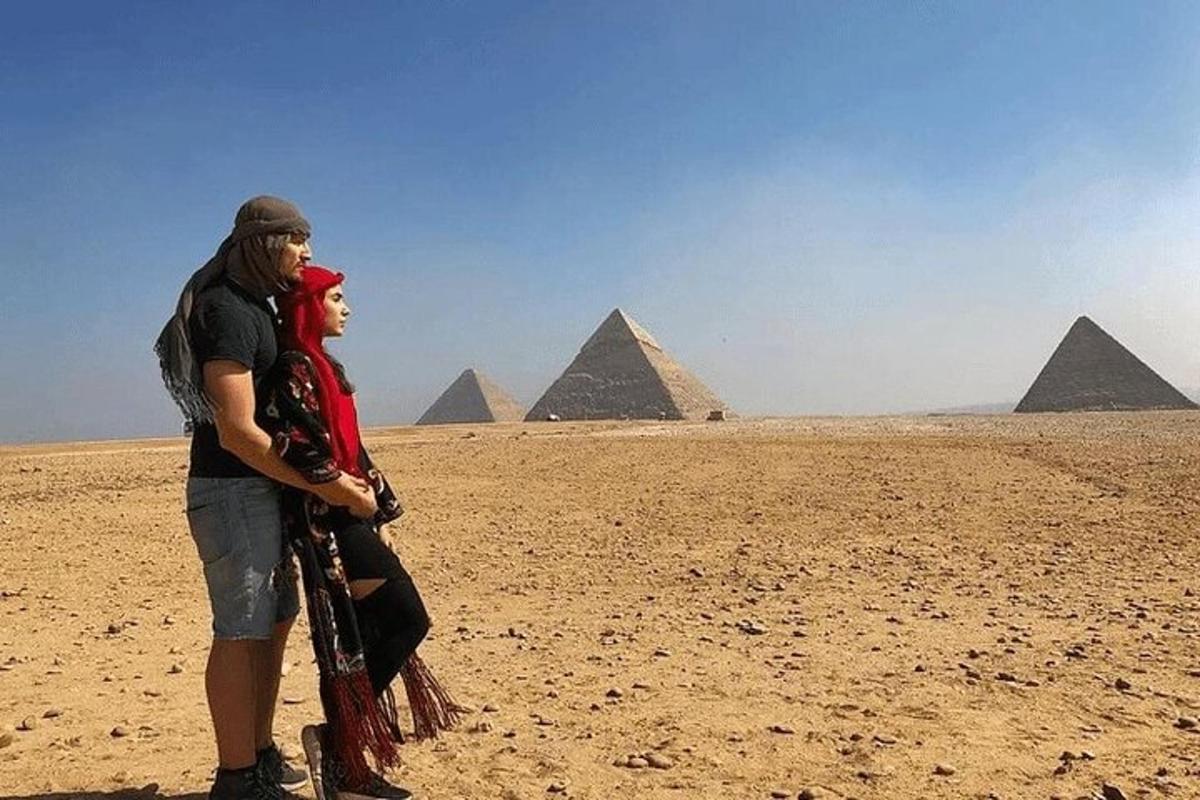 un uomo e una donna in piedi davanti alle piramidi