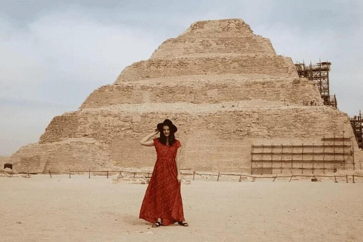 una donna in un vestito rosso in piedi davanti a una piramide
