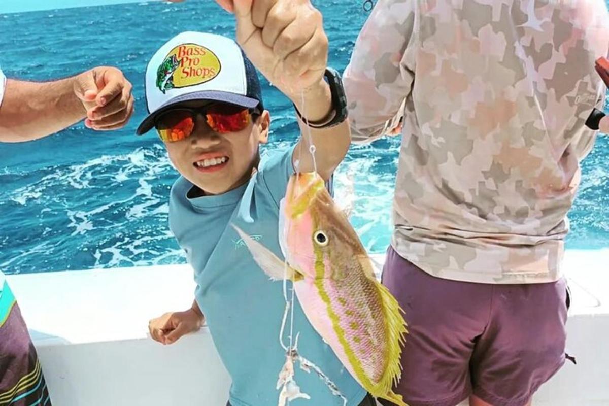 isang batang lalaki na may hawak na isda sa isang bangka