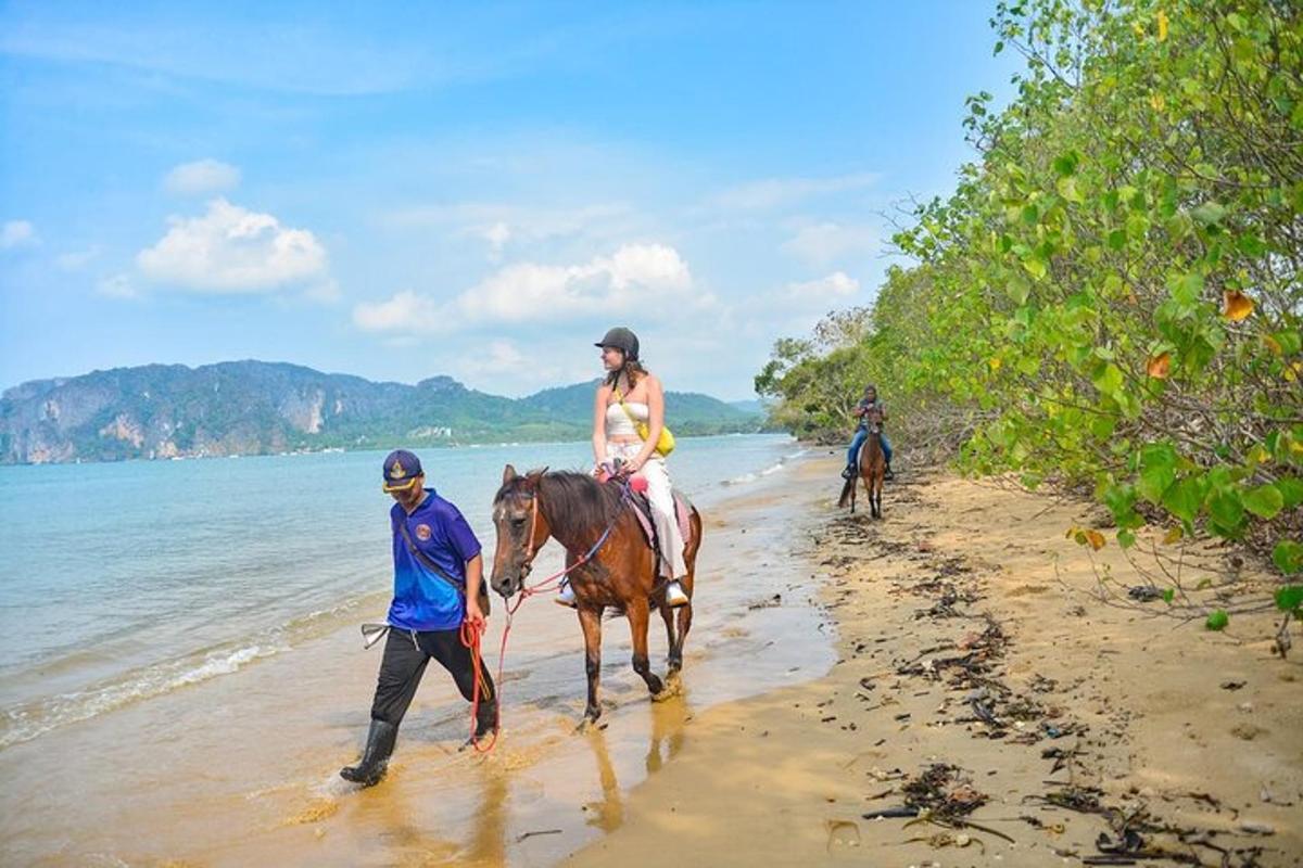 Un hombre guiando a una mujer a caballo por la playa.
