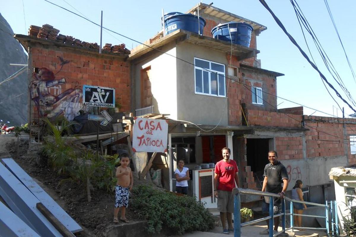 un grup de persones dretes davant d'una casa