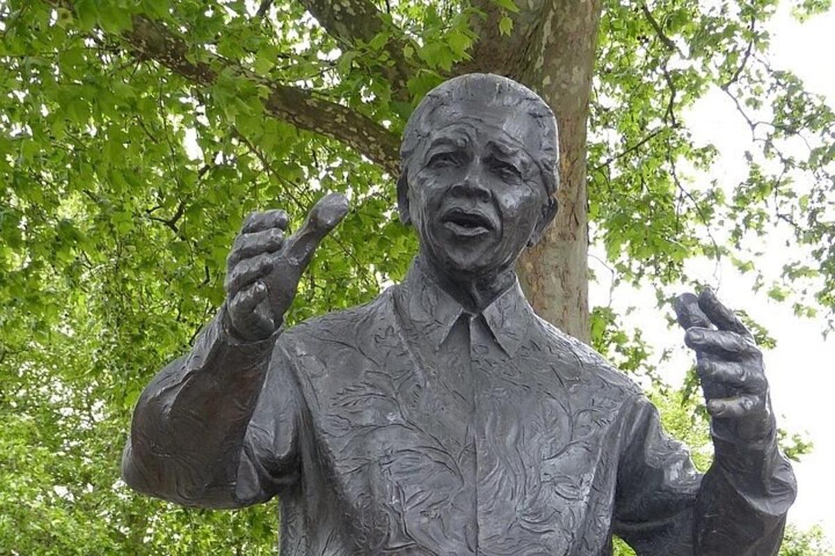 patung seorang pria berdiri di samping pohon