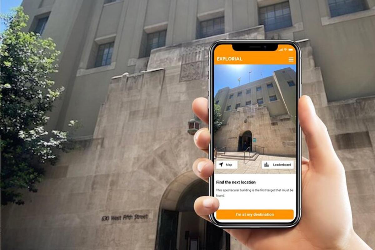 osoba trzymająca telefon komórkowy przed budynkiem