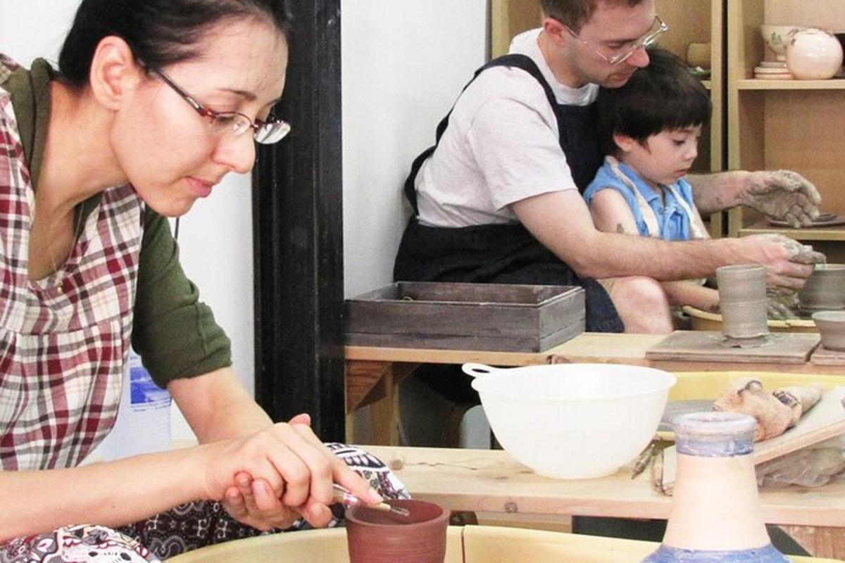 uma mulher e dois homens trabalhando em uma oficina de cerâmica