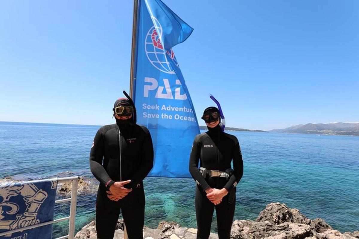 Δύο άτομα με στολές κατάδυσης στέκονται μπροστά στον ωκεανό