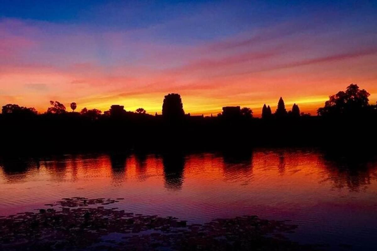 Una puesta de sol sobre un cuerpo de agua con árboles.