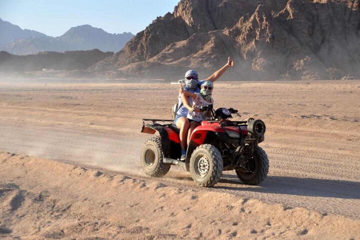Dos personas viajando en un quad por el desierto