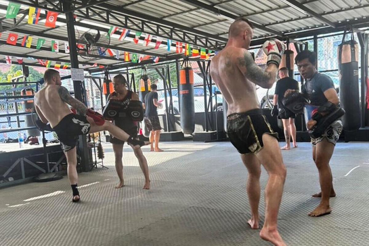 Un grupo de hombres de pie en un gimnasio con equipo de boxeo.