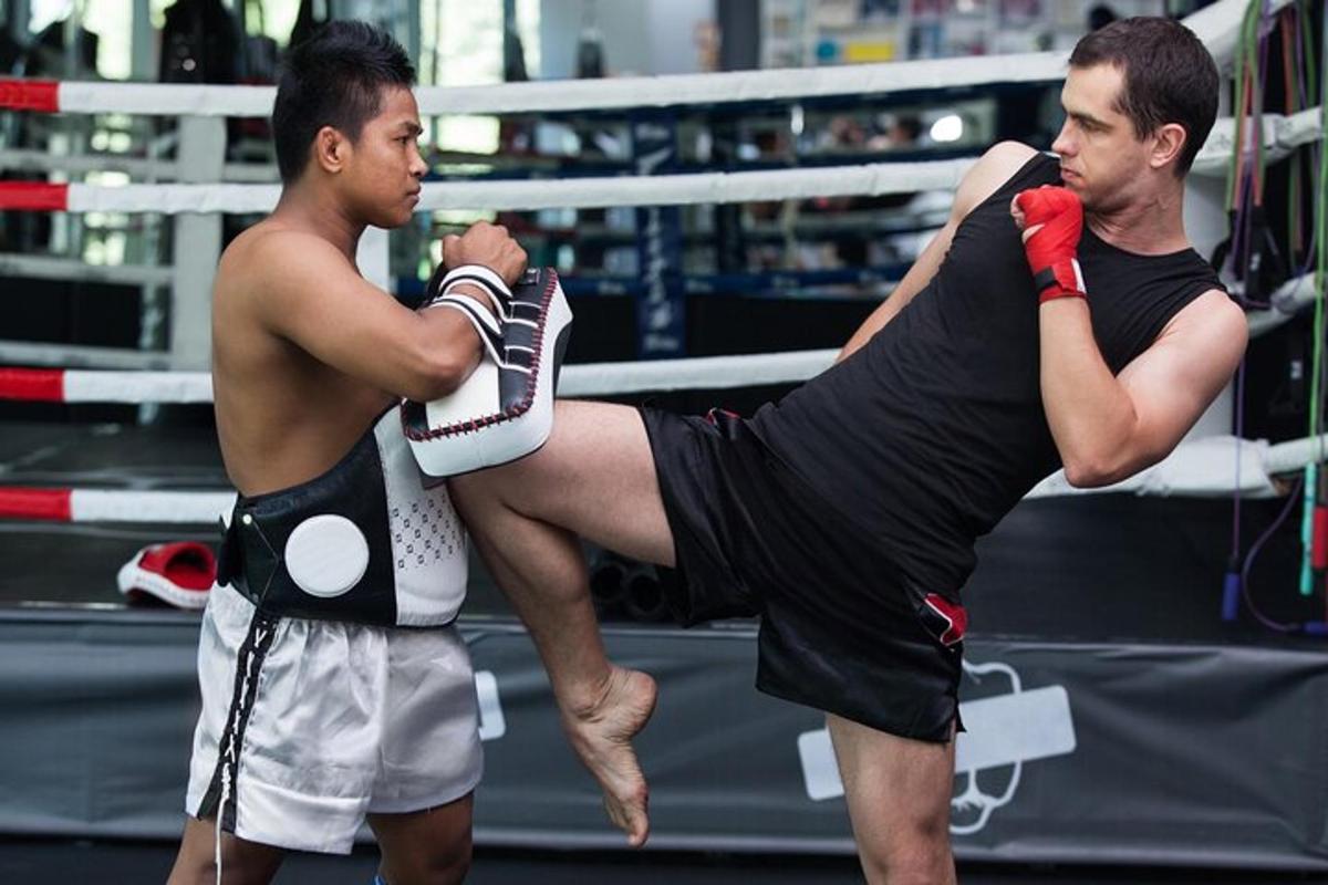Dos hombres de pie en un ring de boxeo con una pierna en el aire