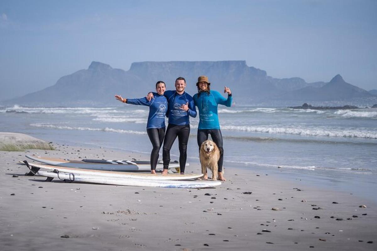 three people and a dog on a surfboard on the beach