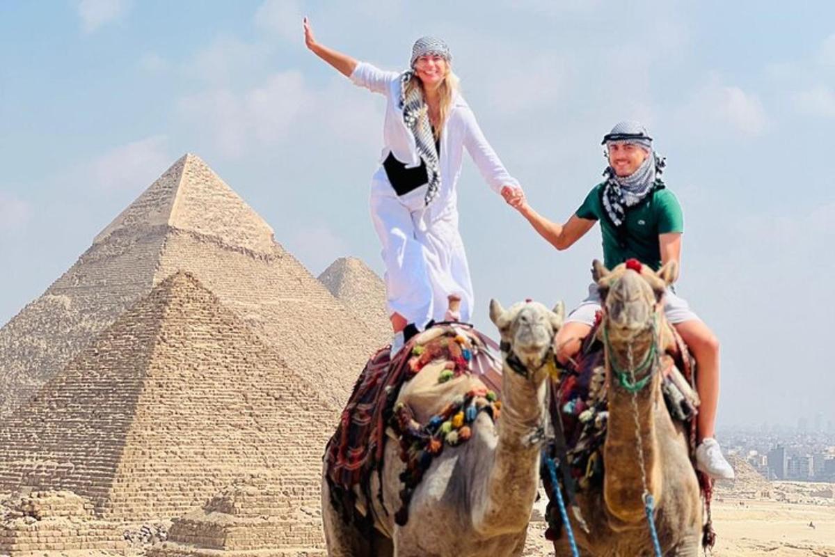 dva lidé jedoucí na koních před pyramidami