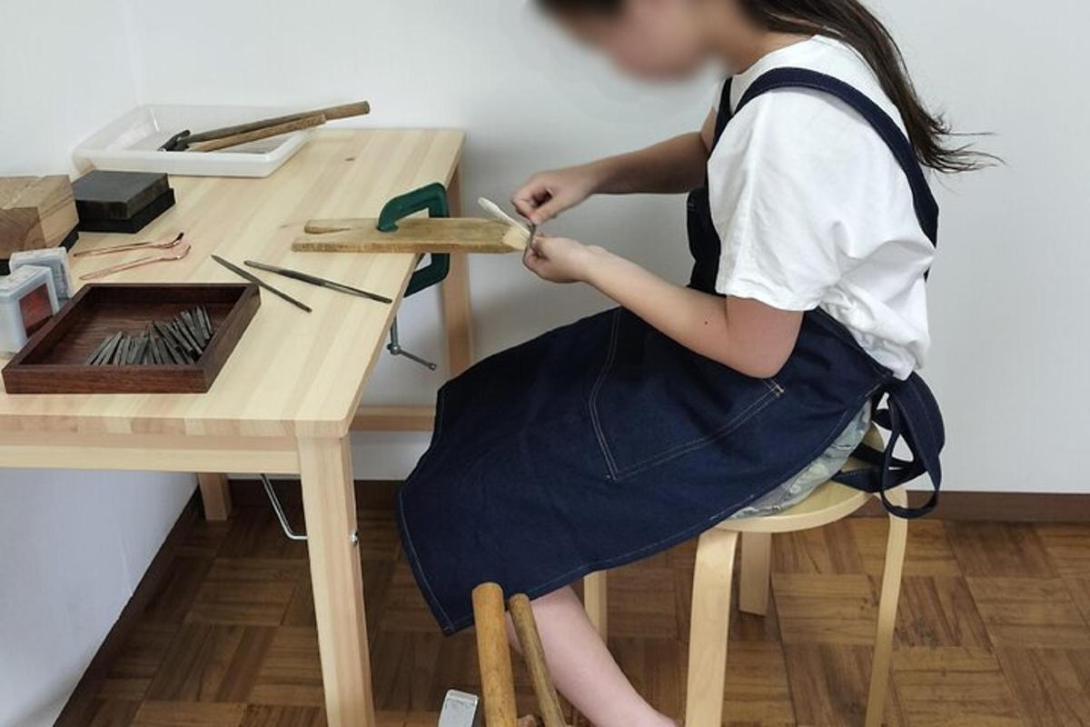 mladá dívka sedí u stolu a řeže dřevo
