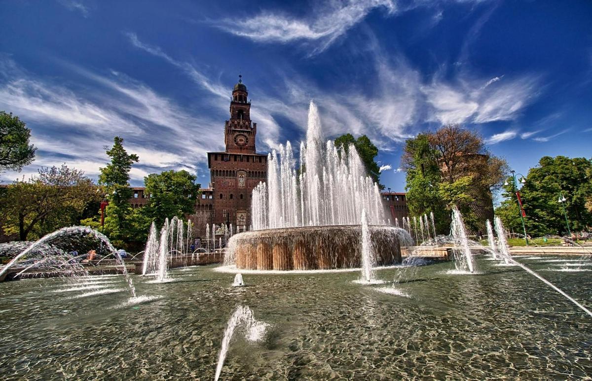 una fuente frente a un edificio con una torre de reloj