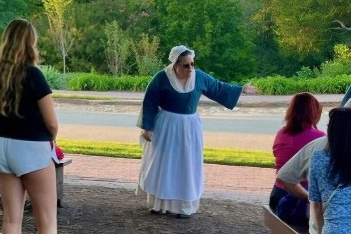 a woman is pointing at something in a park