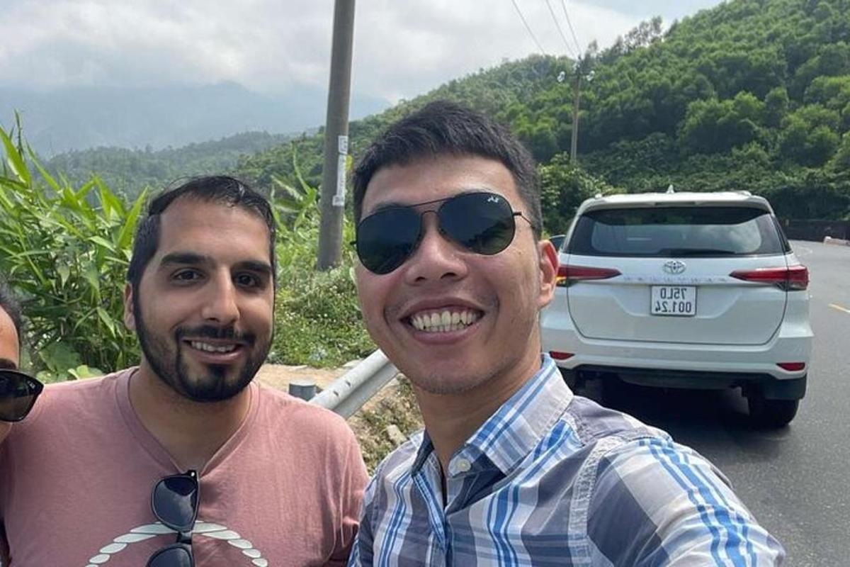 dois homens estão posando para uma foto na frente de um carro