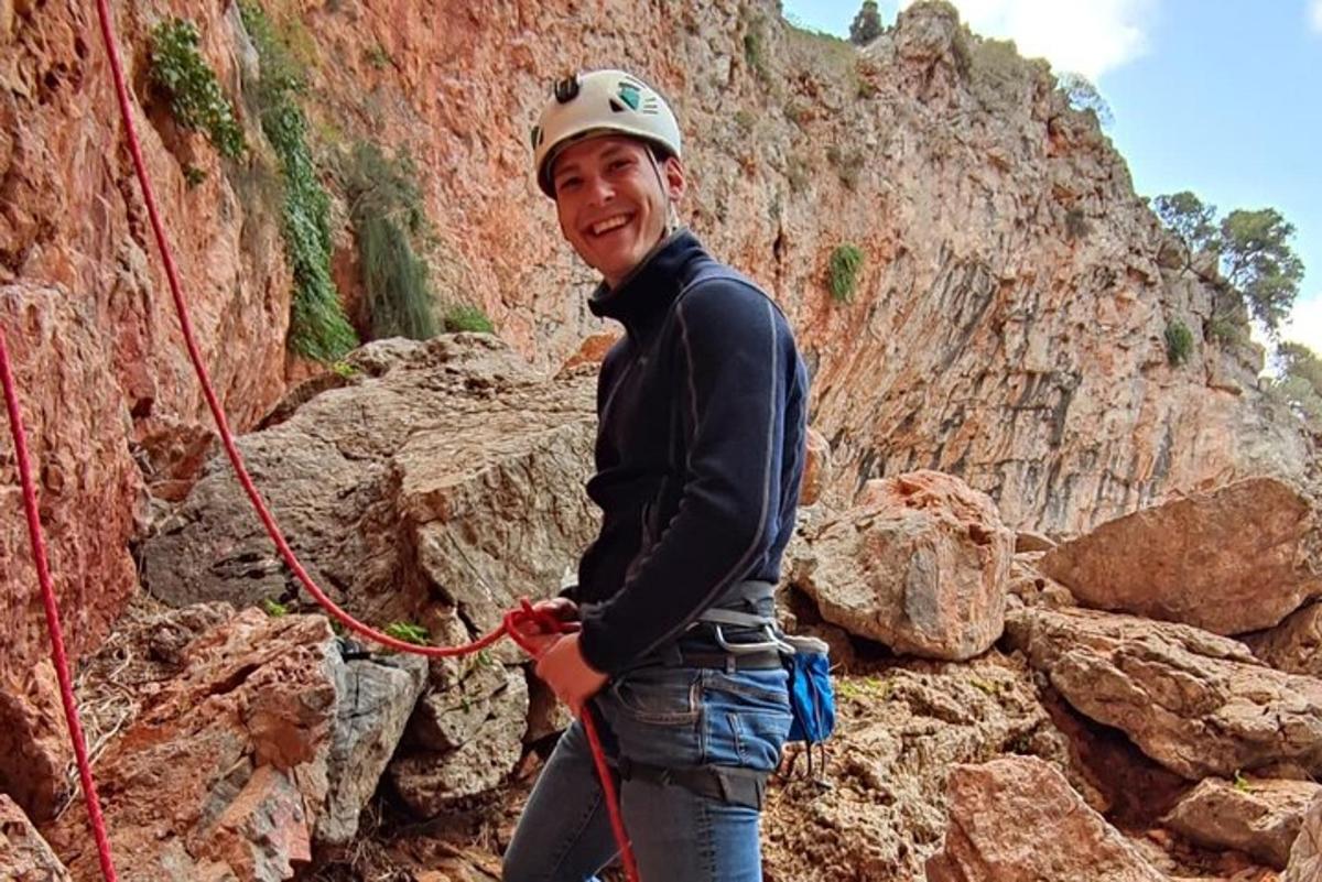 um homem está segurando uma corda vermelha em uma montanha