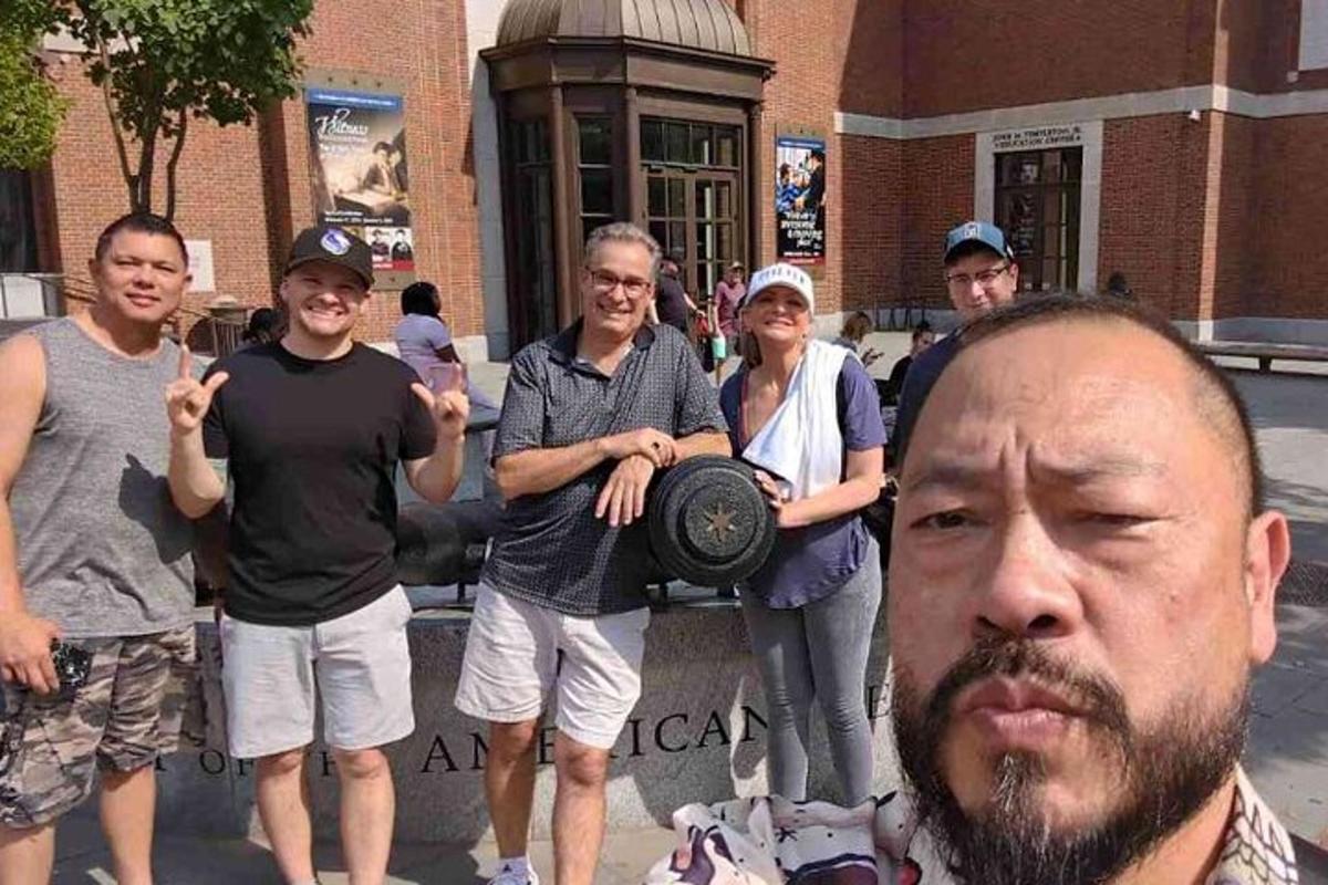 Un grupo de personas de pie frente a un hombre.