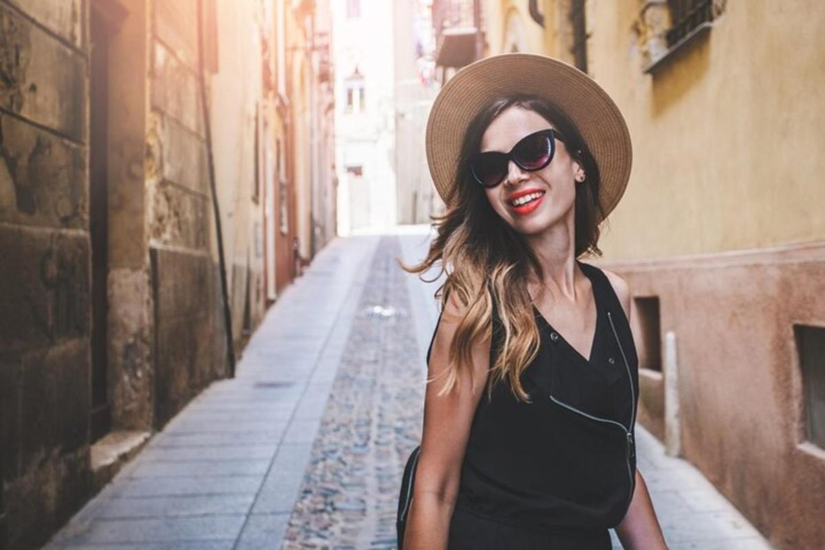 una donna che indossa un cappello e occhiali da sole che cammina lungo una strada