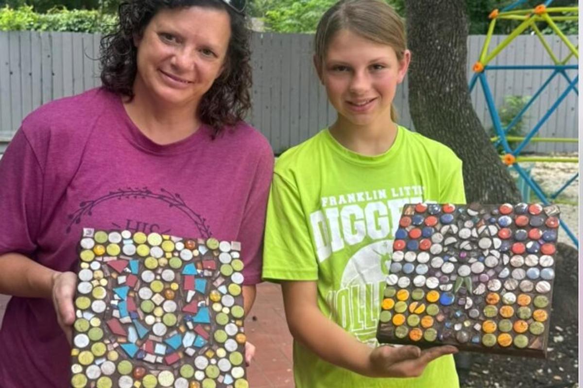 a woman and a girl holding two pieces of art
