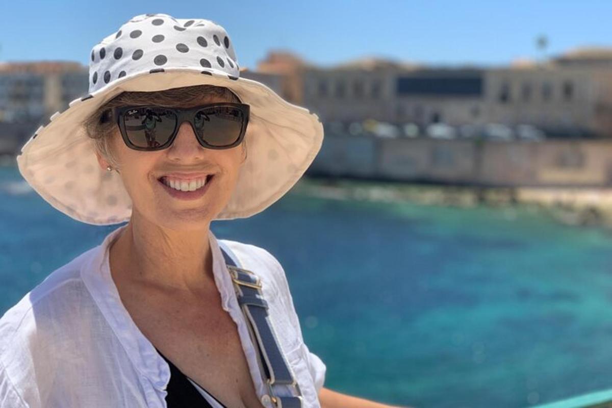 žena s kloboukem a slunečními brýlemi u vody