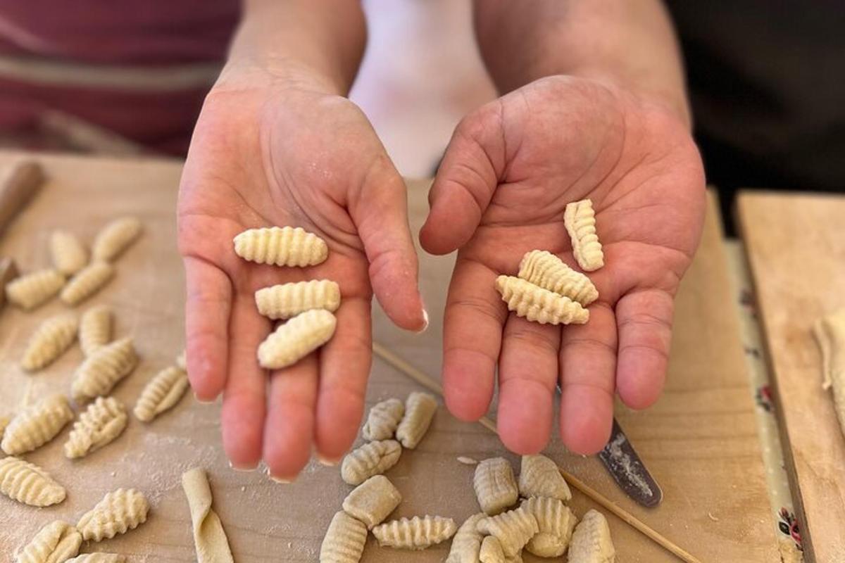 seseorang menghulurkan tangan mereka dengan pasta di atas meja