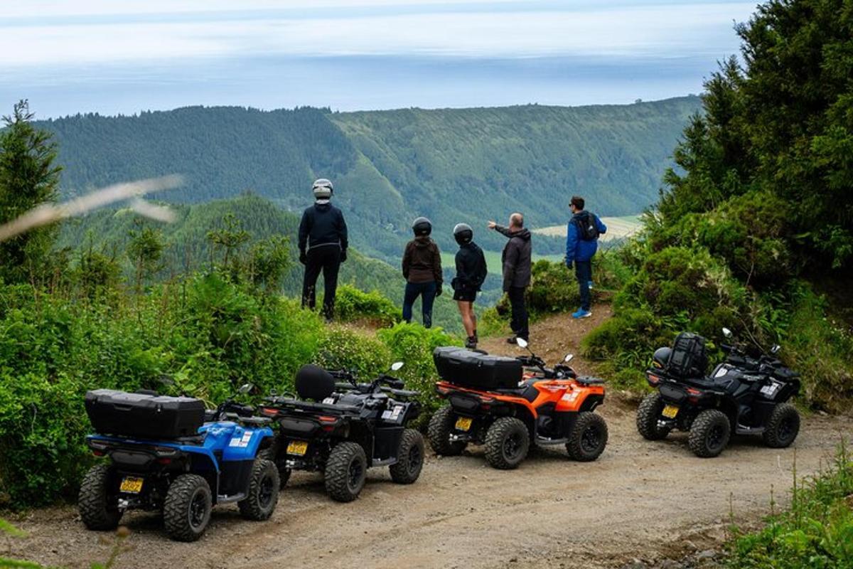 a group of people standing on a dirt road with atvs