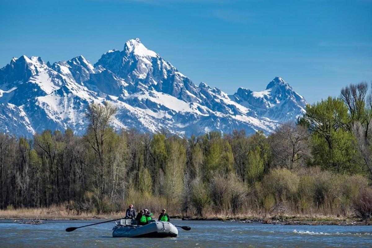 a group of people in a boat on a river with mountains