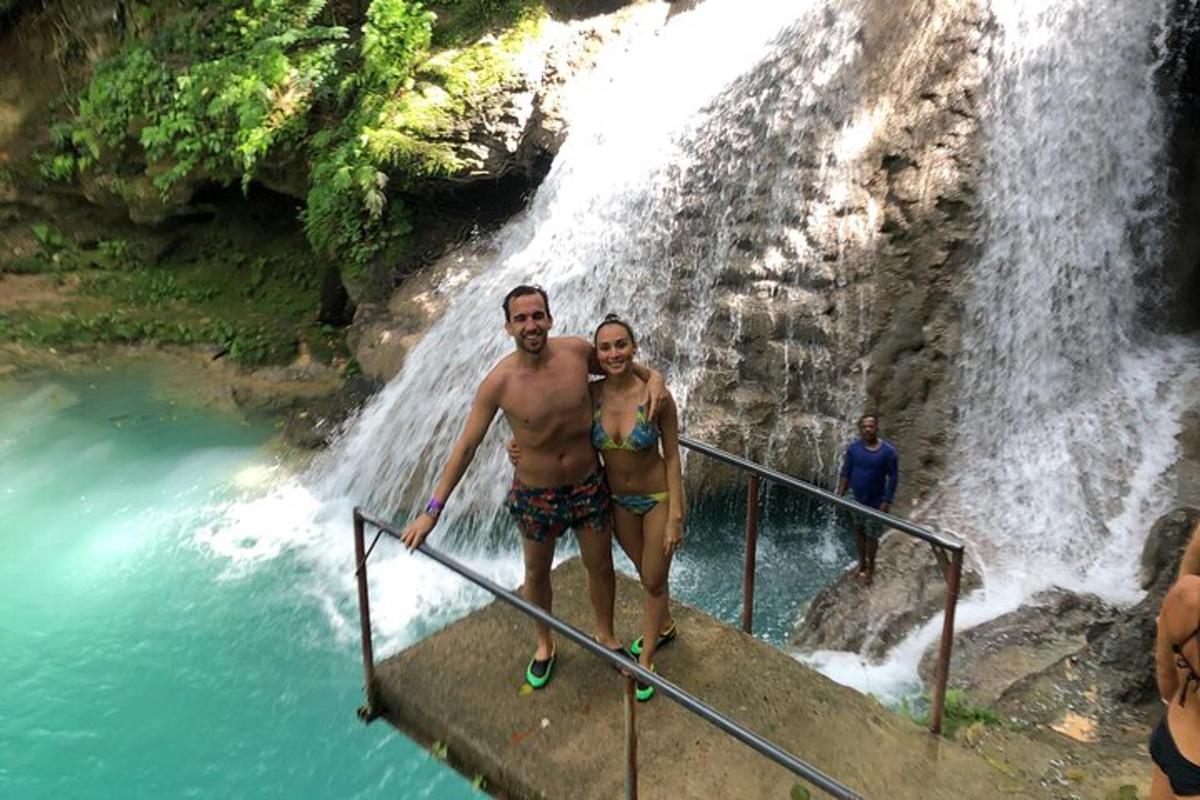 a man and a woman standing in front of a waterfall