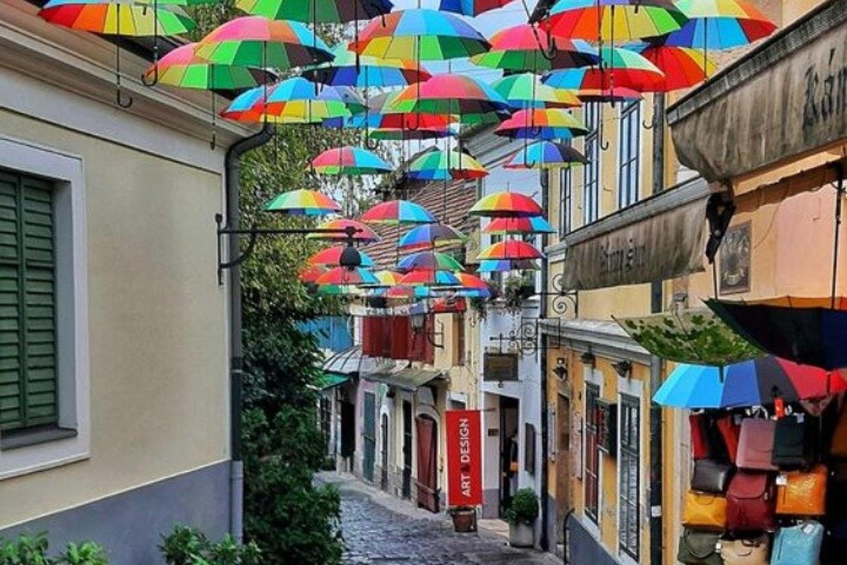 Un montón de paraguas de colores colgando sobre una calle.