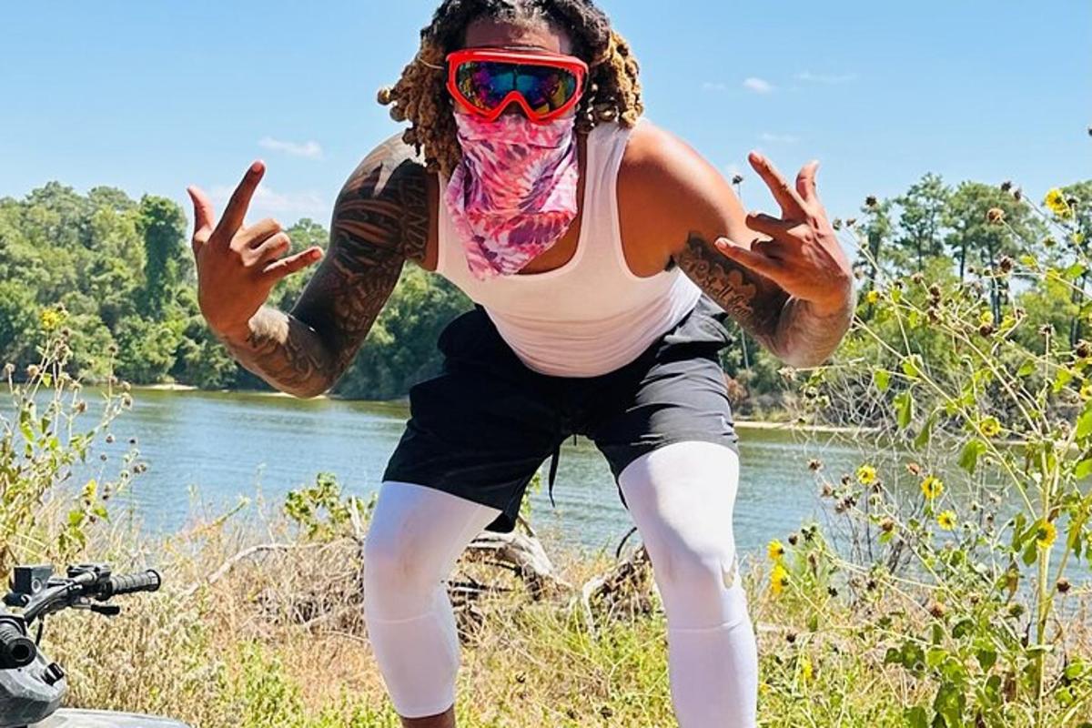 a woman wearing a vest and sunglasses with her hands up